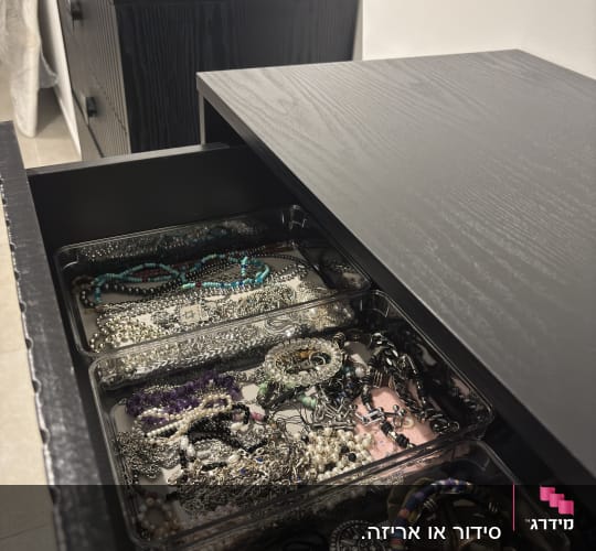 מגירות עם תכשיטים מאורגנים בארון שחור